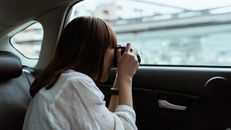 Woman taking photo on photo camera from car backseat