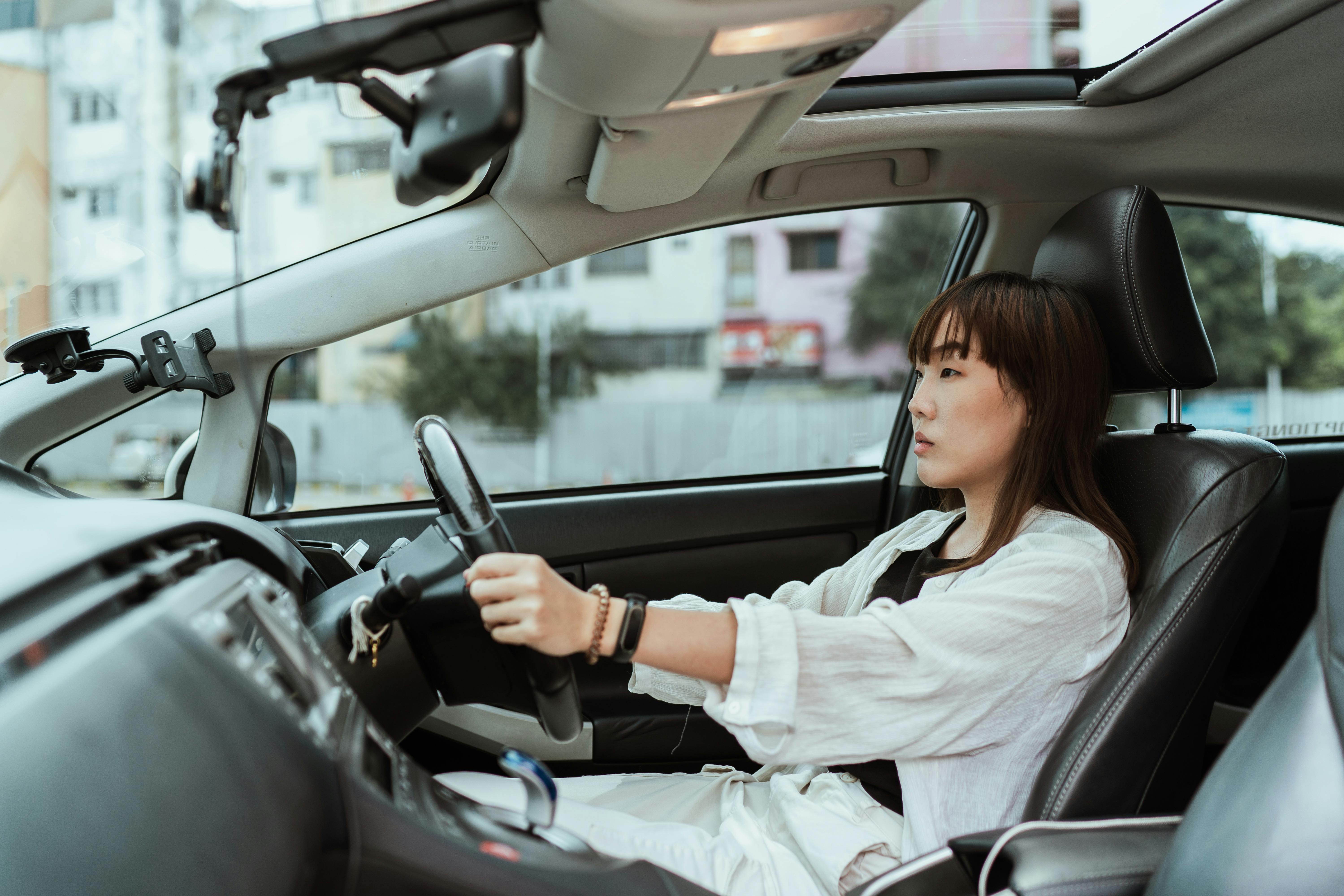 serious asian woman driving right hand car