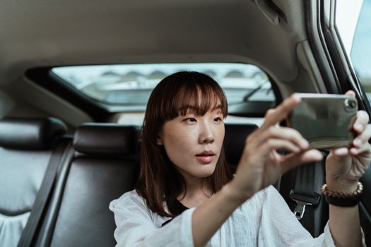 一名女子在汽车后座上用智能手机拍照