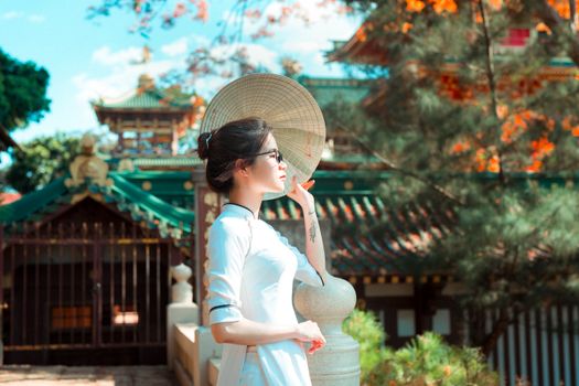 在日本佛塔前，一位身穿白裙、头戴草帽的女子，正享受着阳光明媚的日子