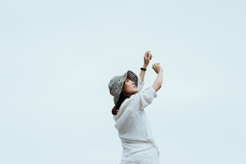 Stylish woman with arms raised against cloudless sky