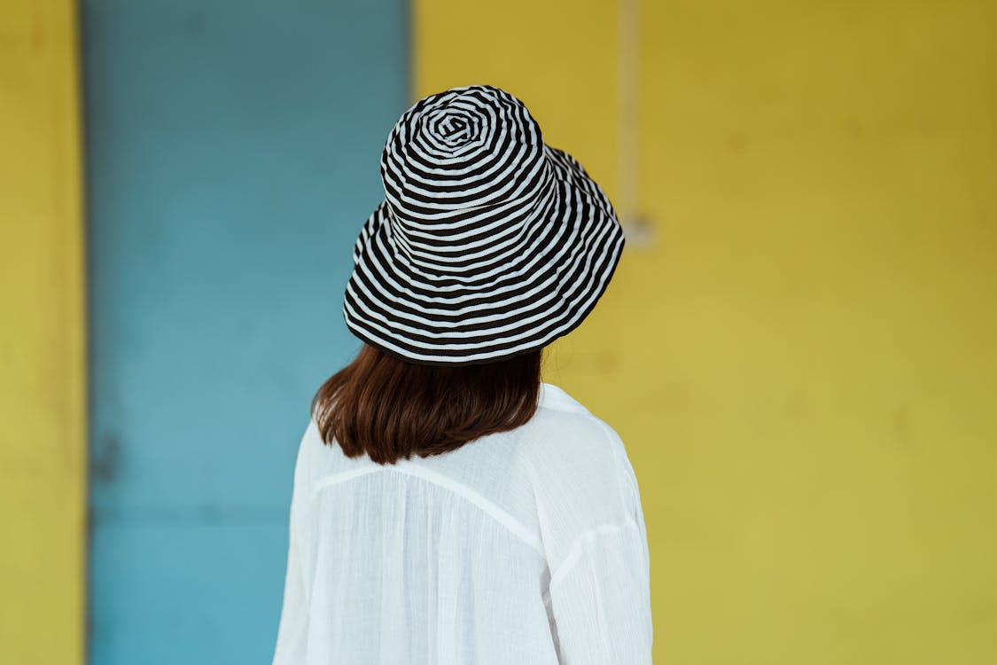 Unrecognizable woman in trendy hat against yellow wall · Free Stock Photo