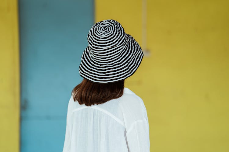 Unrecognizable Woman In Trendy Hat Against Yellow Wall