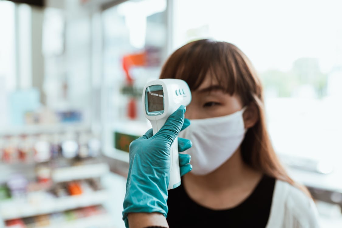 Free Woman Wearing a Face Mask Getting her Temperature Checked Stock Photo