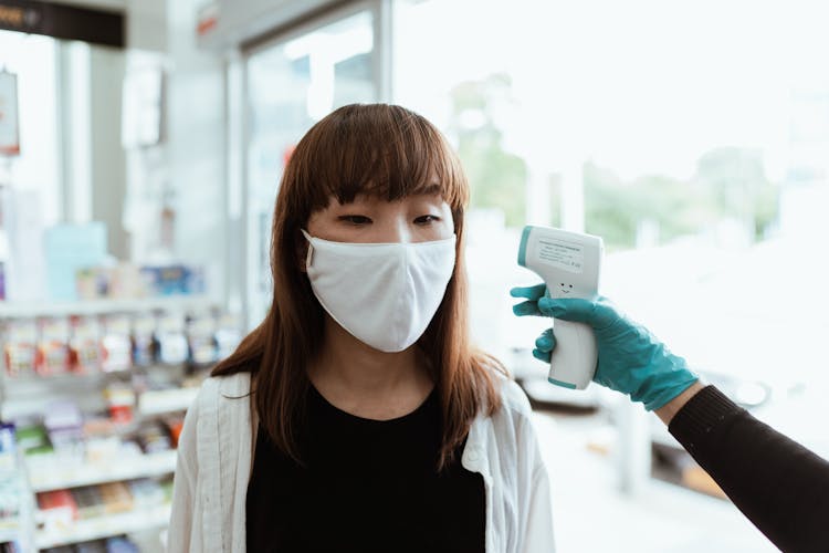 Woman Wearing A Face Mask Getting Her Temperature Checked