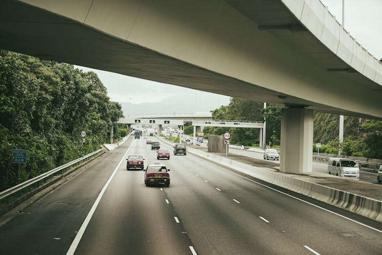 Cars Driving On Road Under City Bridge