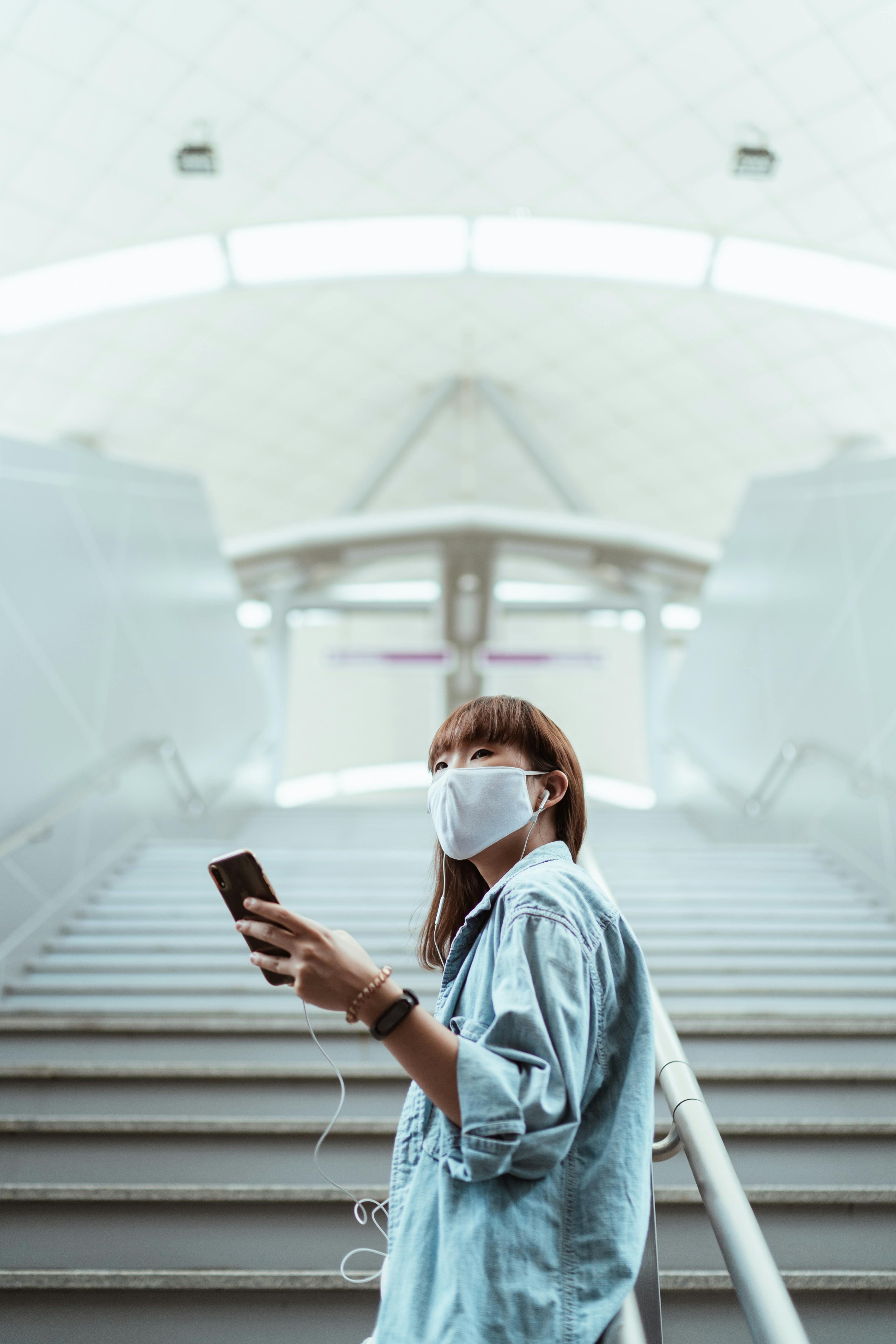 woman with a face mask holding her smartphone