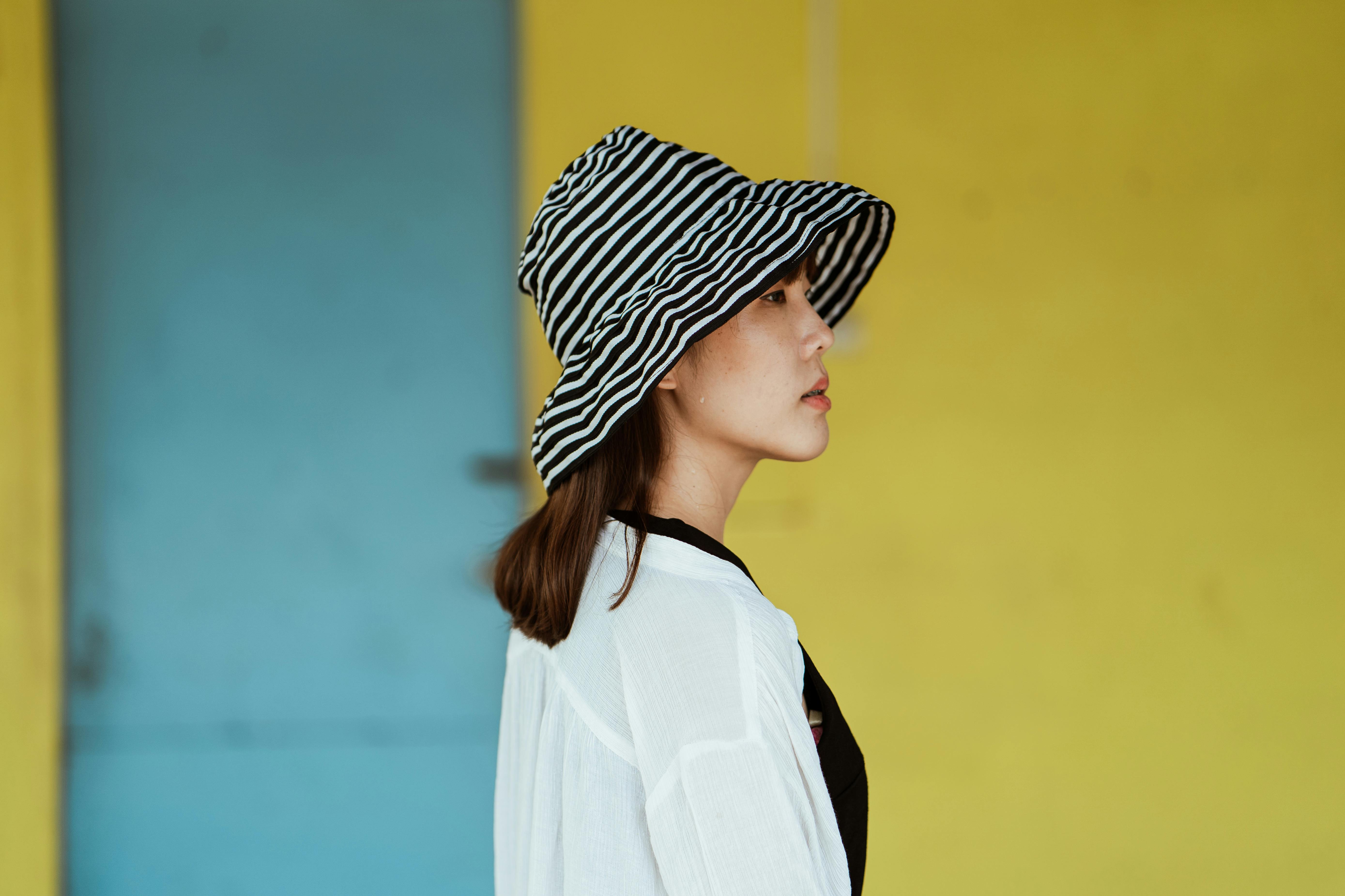 一名女子戴着条纹帽子，在色彩缤纷的户外背景下露出侧面轮廓