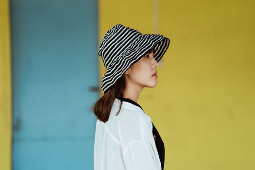 一名女子戴着条纹帽子，在色彩缤纷的户外背景下露出侧面轮廓