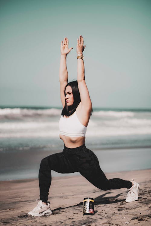 Woman in a White Sports Bra Stretching at the Beach