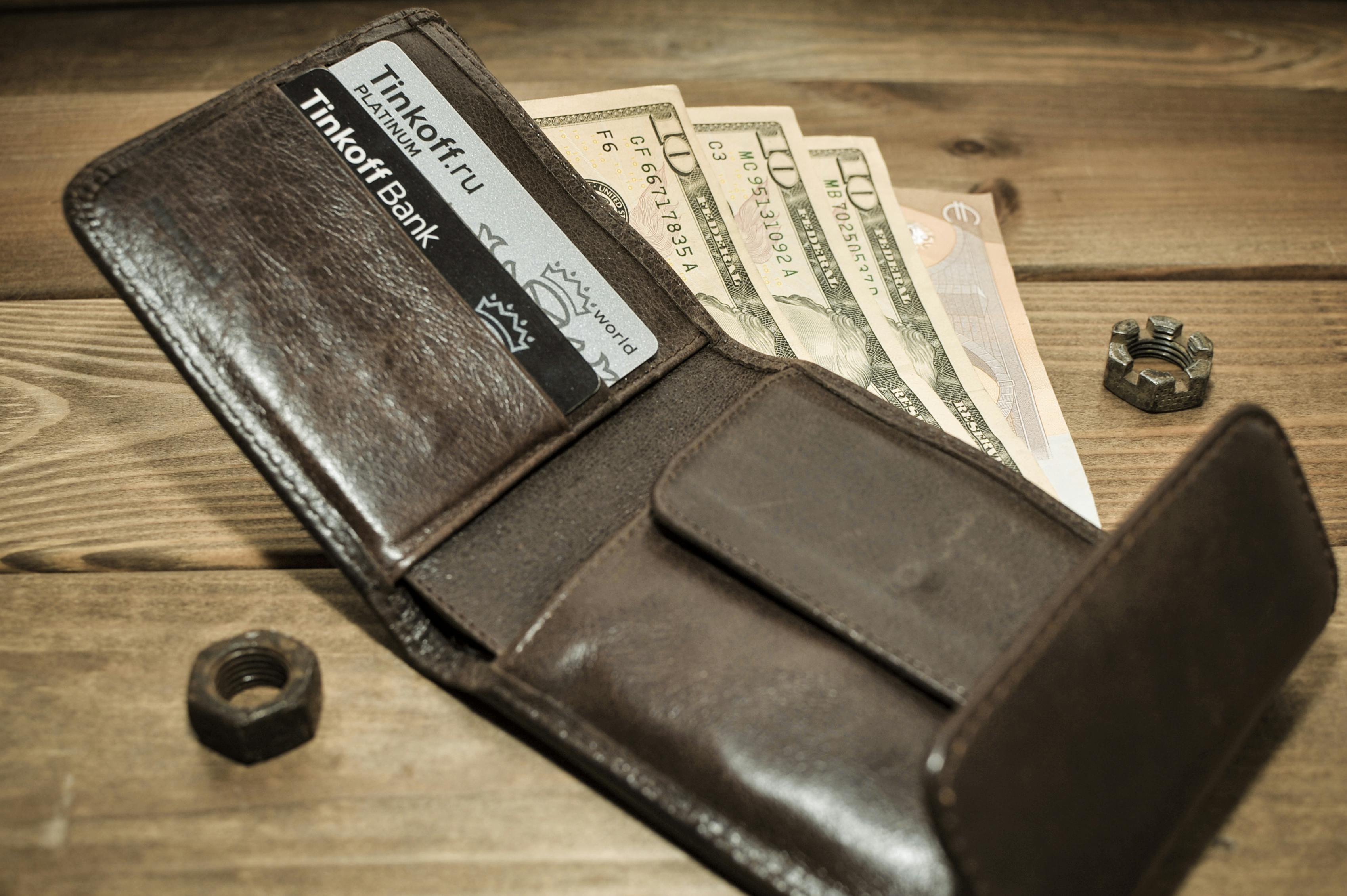 a brown leather wallet with dollar bills