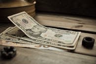 一叠美元钞票的特写镜头，聚焦于一张质朴的木桌