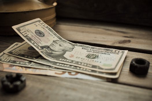 A stack of US dollar bills on a rustic wooden table close-up view.