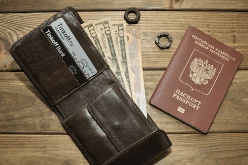 Photograph of a Leather Wallet with Dollar Bills Beside a Passport