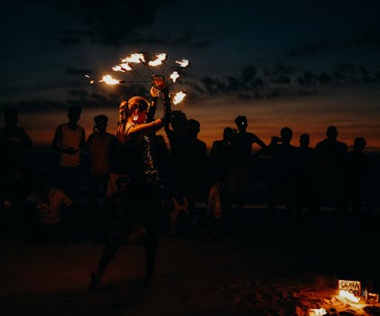 A mesmerizing fire dancer entertains a crowd at sunset on Arambol Beach, India.
