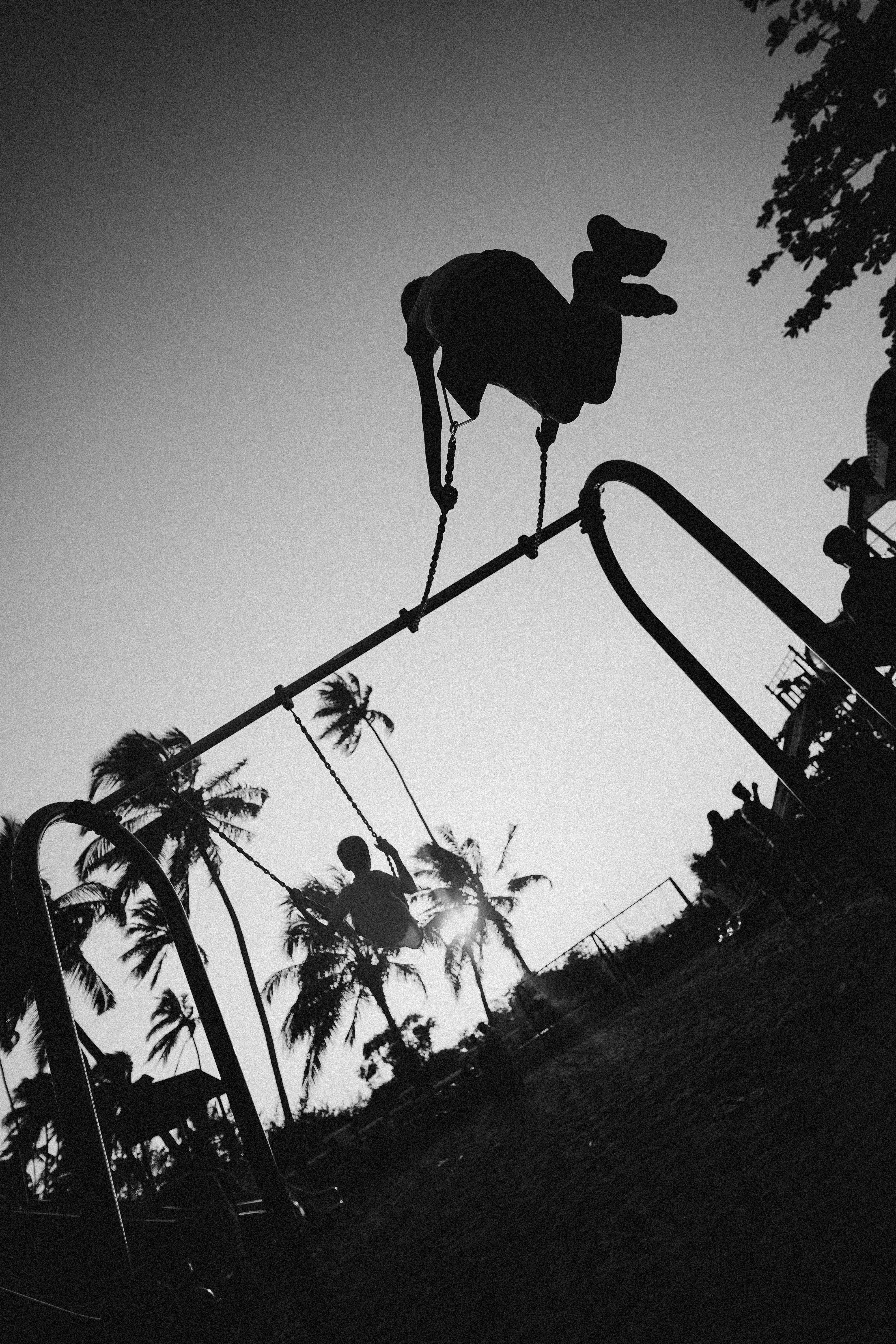 monochrome photo of children playing on swing