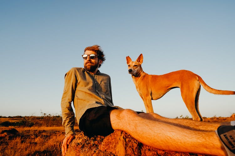 Photo Of Man Sitting On Rock With His Dog