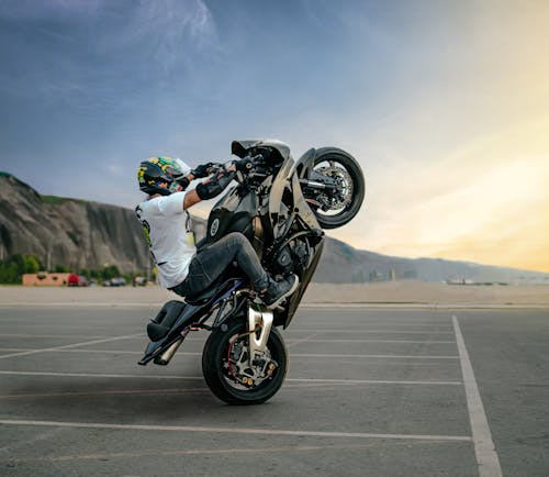 Free Faceless biker performing trick on motorbike on road Stock Photo