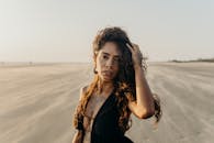 日落时分，一位有纹身的沉思的年轻女子站在沙滩上，捕捉到了一个宁静的时刻