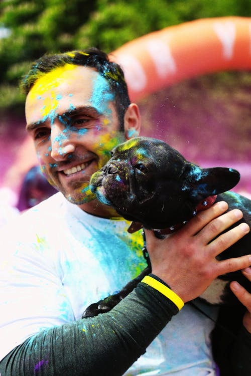 Photo of a Man and His Dog Covered in Colored Powder