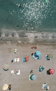Aerial shot of sunbathers and colorful umbrellas on a Venetian beach, showcasing summer vibes.