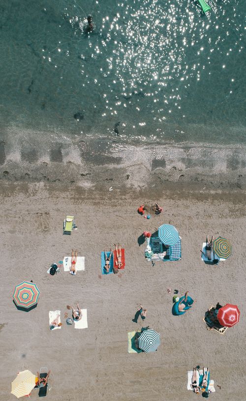 Free Aerial shot of sunbathers and colorful umbrellas on a Venetian beach, showcasing summer vibes. Stock Photo
