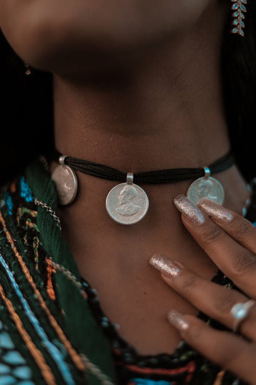 Close-Up Photo of a Woman Touching Her Necklace with Coins