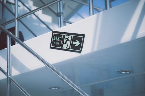Free From below of rectangular signboard with EXIT title and symbol of running figure near stairs with handrail in modern house Stock Photo