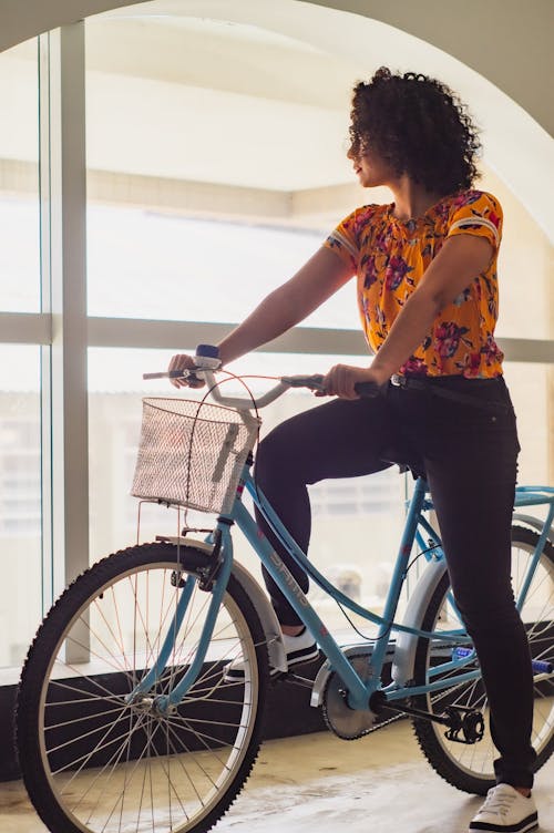 Anonymous ethnic woman on bicycle in building