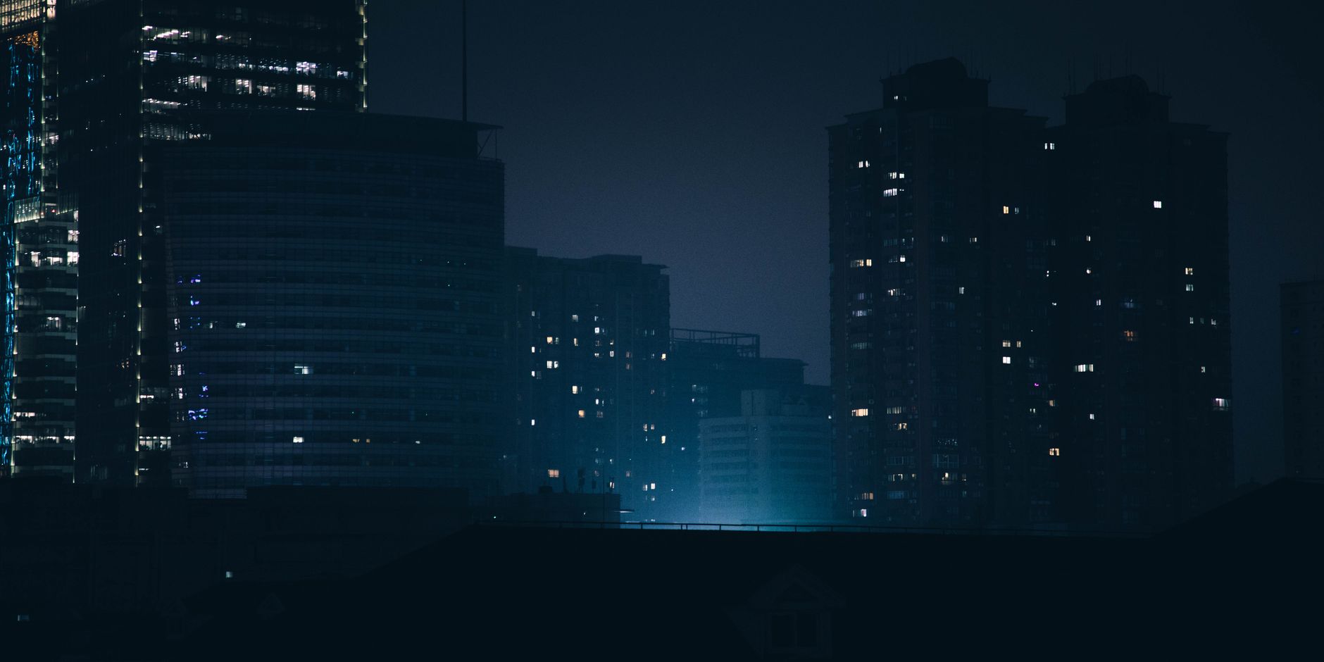 Dark nighttime silhouette of Shanghai highrises illuminating the urban skyline.