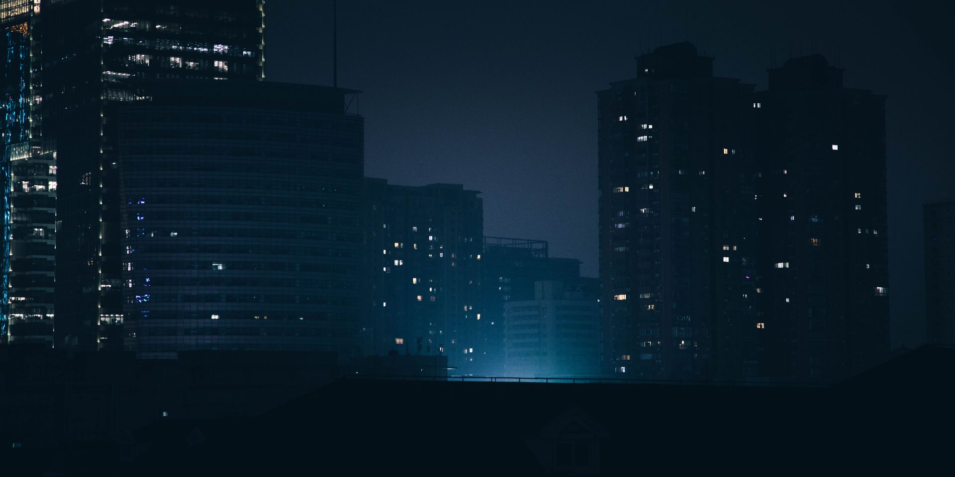 Dark nighttime silhouette of Shanghai highrises illuminating the urban skyline.