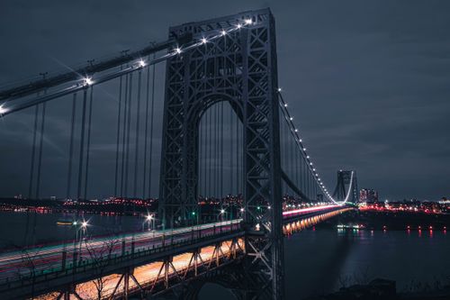 Free Capture of the illuminated George Washington Bridge at night with vibrant light trails along the Hudson River. Stock Photo