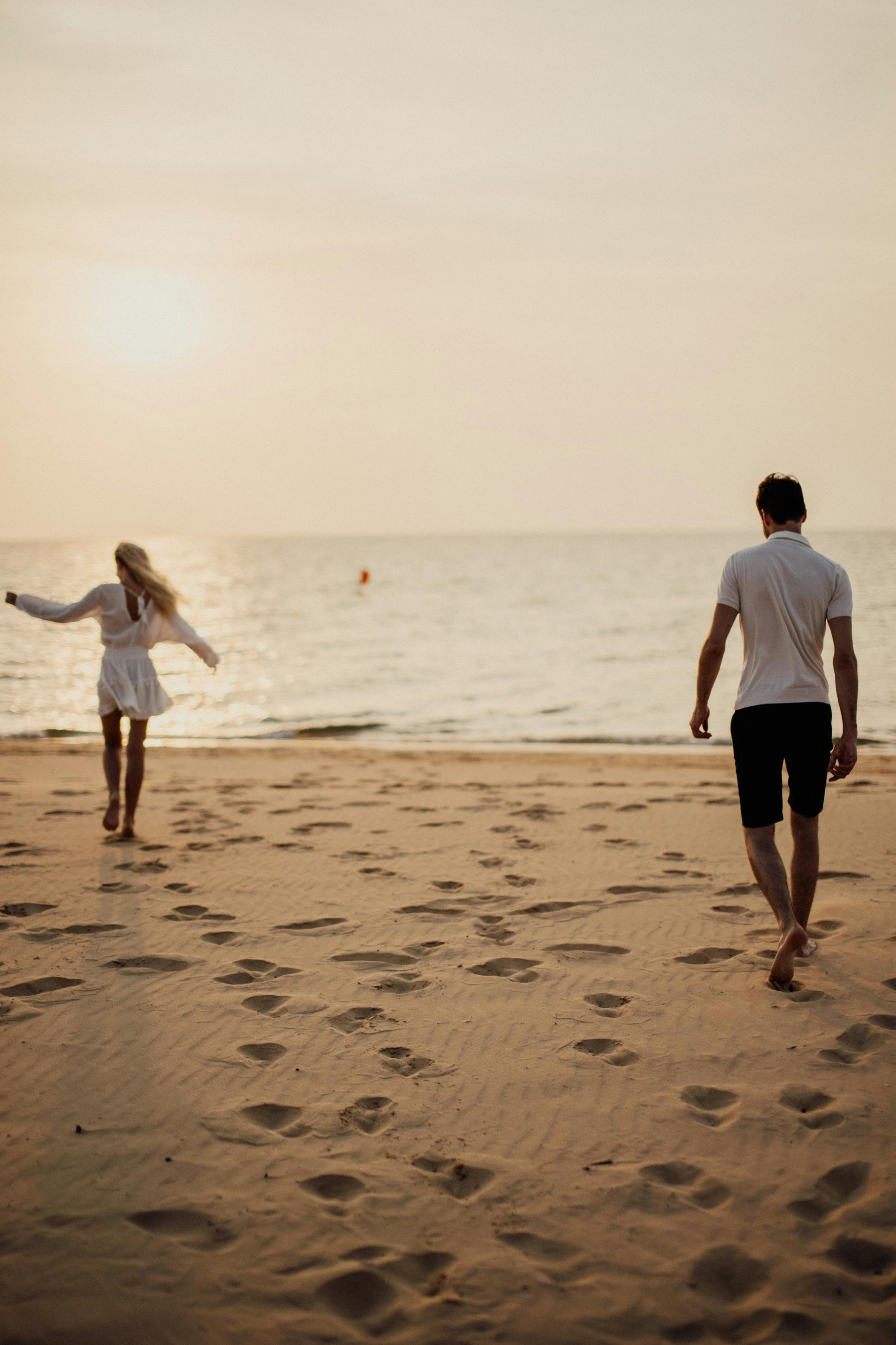 man and woman walking on beach