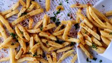 Heap of delicious crunchy fried potatoes spilled on table