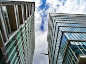 低角度视角下，现代摩天大楼的玻璃外墙映照着多云的天空