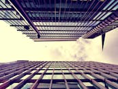 从低角度仰望现代摩天大楼，玻璃外墙映照着天空，展现城市建筑的魅力