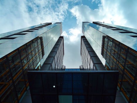 Low-angle view of sleek, modern skyscrapers with glass facades under a blue sky.