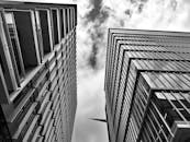 低角度拍摄的未来派摩天大楼，玻璃立面映衬着布满云彩的天空