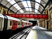 一座充满活力的红桥与历史悠久的火车站上停靠的时尚火车形成鲜明对比，展现了旅行与建筑的魅力