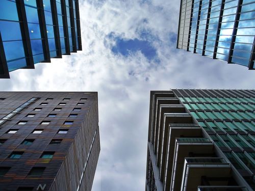 Free Dynamic upward view of diverse modern skyscrapers framing a cloudy sky. Stock Photo