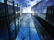 现代摩天大楼的立面透视图中，玻璃反射着云和天空