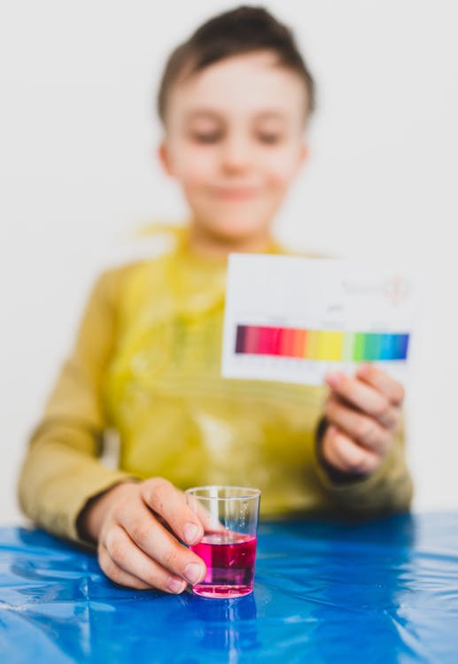 Content kid with spectrum palette and bright liquid in apartment