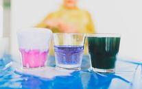 Unrecognizable boy near glasses with colorful liquids and chemical processes