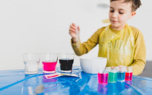 Boy mixing colorful liquids placed on table