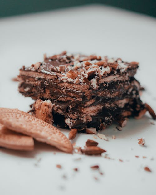 Closeup of delicious sweet chocolate cake decorated with almonds and served on plate with crispy cookies