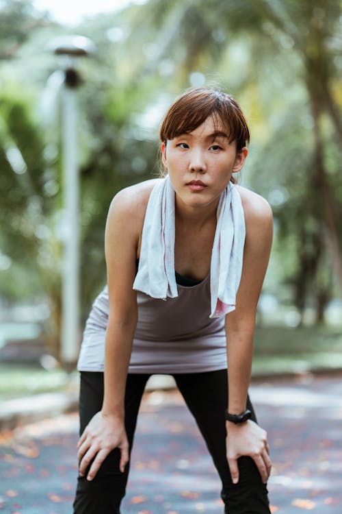 Free Asian sportswoman in smart watch having break after workout outdoors Stock Photo