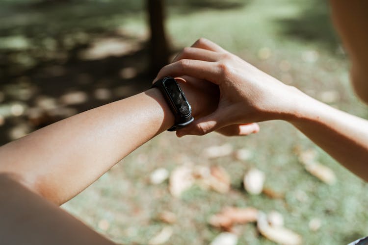 Crop Anonymous Person Showing Wearable In Park With Faded Leaves