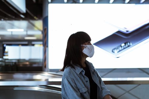 Free Profile of a woman in a mask, indoors with digital display, city life. Stock Photo