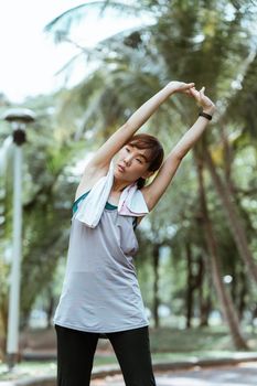 在宁静的公园里，一名穿着运动服的年轻女子正在做伸展运动