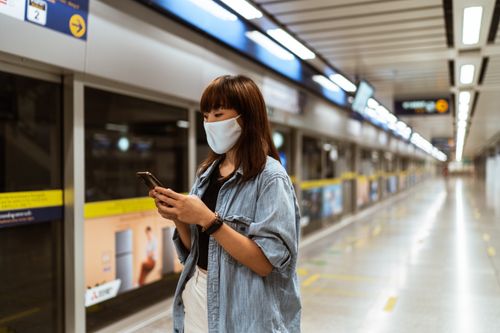 Free Young woman in a face mask using a smartphone at an empty subway station. Stock Photo